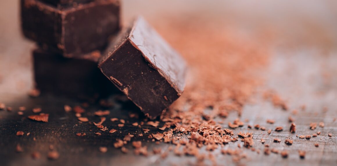 Dunkle Schokolade mit Kakao auf einem Holztisch, vegane Halbbitter-Optik