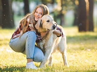 Person umarmt liebevoll ihren Hund auf einer Wiese