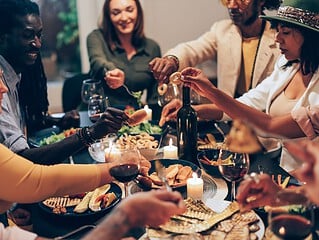 Menschen sitzen an einem Esstisch und diskutieren angeregt beim Essen