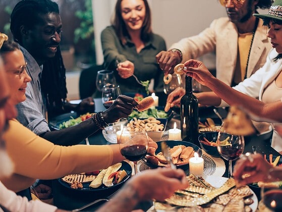Menschen sitzen an einem Esstisch und diskutieren angeregt beim Essen