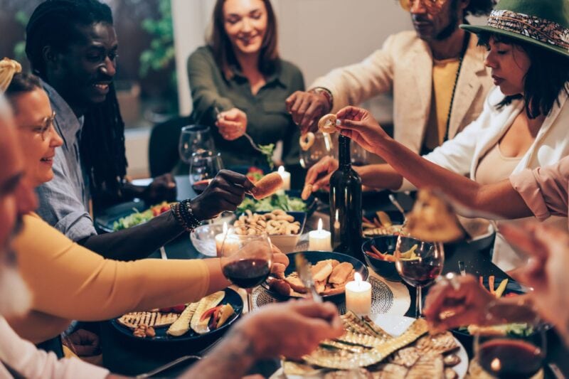 Menschen sitzen an einem Esstisch und diskutieren angeregt beim Essen