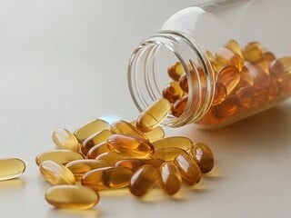 Supplement capsules spilling from a bottle onto a light surface