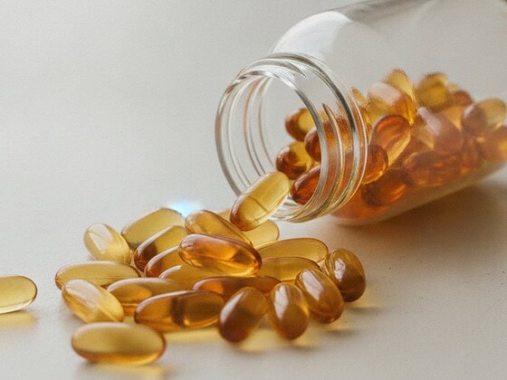 Supplement capsules spilling from a bottle onto a light surface