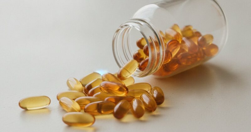 Supplement capsules spilling from a bottle onto a light surface