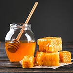 Is honey vegan? - 5 reasons why honey is not vegan Honigglas mit Holzloeffel und Honigwaben auf einem Holztisch