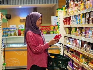 Frau prueft ein Produkt im Supermarkt