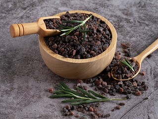 Kala-Namak-Salz in einer Holzschale mit Holzlöffel auf dunklem Stein