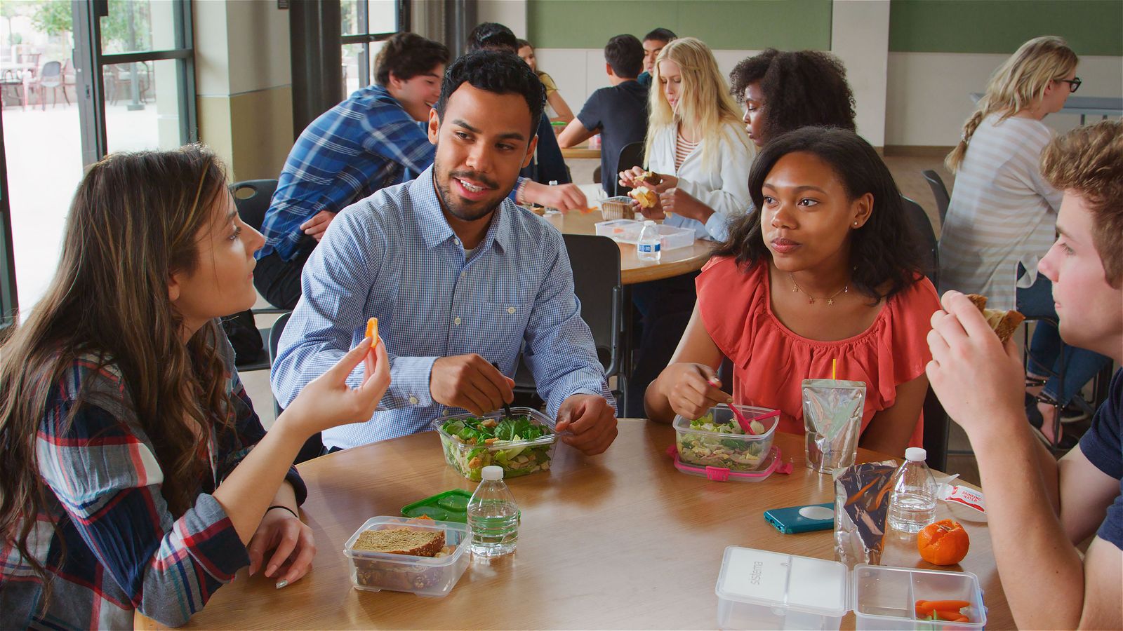 Studierende essen gemeinsam in einer hellen Mensa zu Mittag