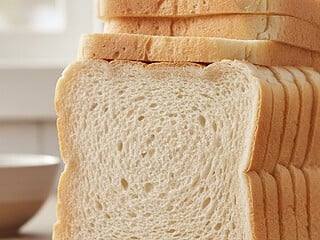 A stack of sliced sandwich bread on a wooden board