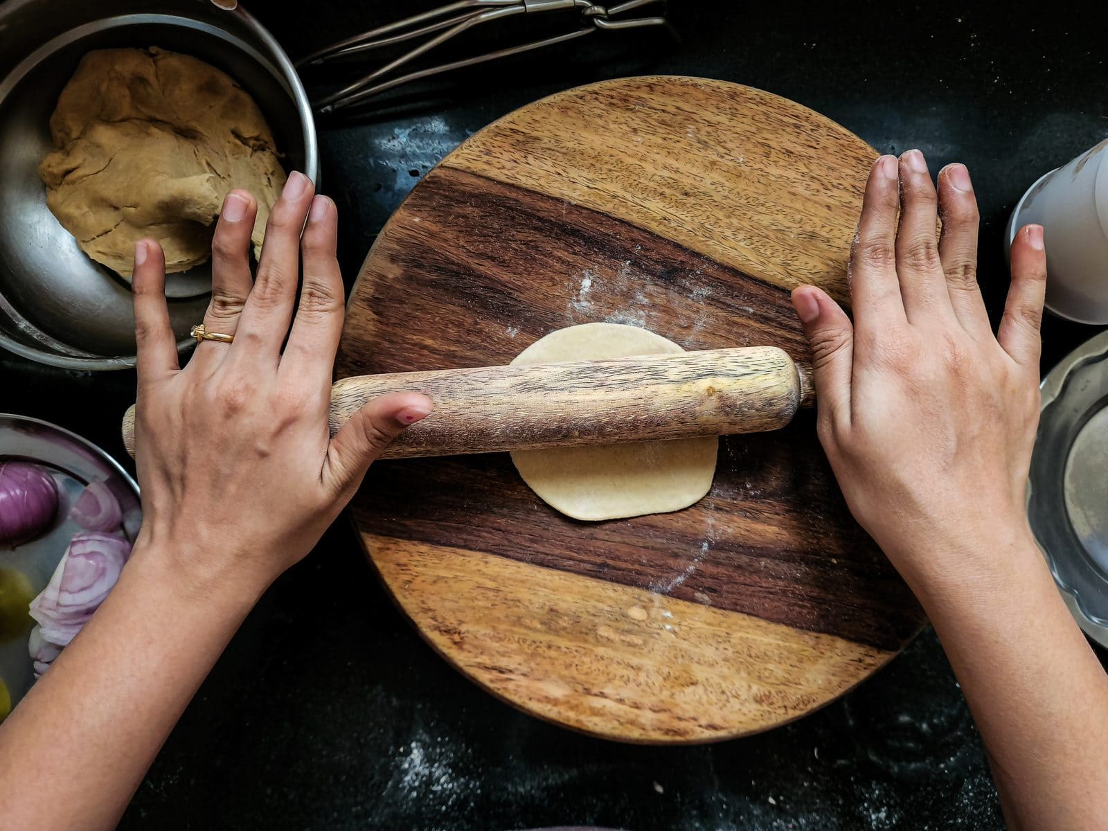 Rolling wheat dough for chapati with a rolling pin