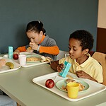 2,53 Milliarden Euro im Jahr: Was pflanzliche Kantinen Deutschland sparen könnten Kinder essen gemeinsam Mittagessen in einer hellen Schulkantine