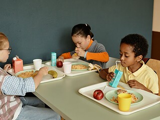 Kinder essen gemeinsam Mittagessen in einer hellen Schulkantine