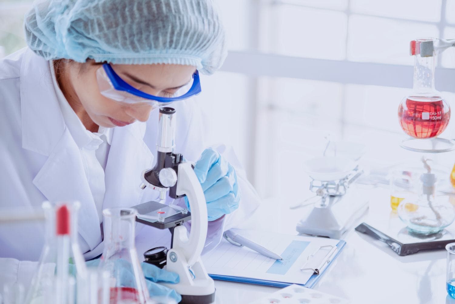 Wissenschaftlerin arbeitet im Labor mit Mikroskop und Zellkulturproben