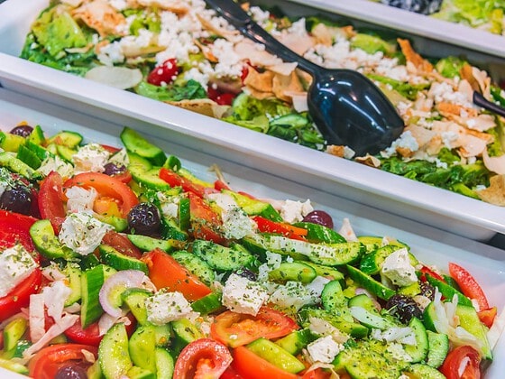 Frische bunte Gemüsesalate mit Tomaten, Gurken und Oliven an einem Buffet