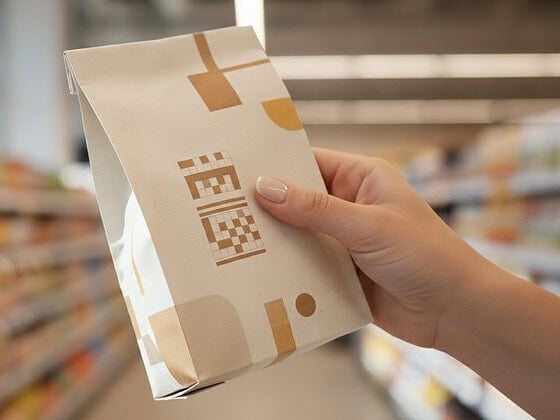 Hand hält eine Lebensmittelverpackung und liest die Zutatenliste im Supermarkt