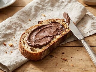 Toast mit Schokocreme und Messer auf einem Frühstückstisch im Morgenlicht