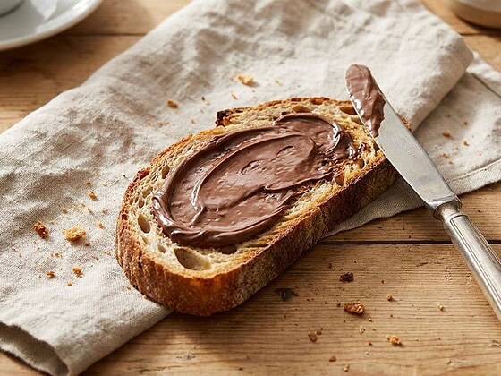 Toast mit Schokocreme und Messer auf einem Frühstückstisch im Morgenlicht