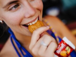 Festivalbesucherin beißt in einen Biscoff-Keks in Medaillen-Form bei Tomorrowland