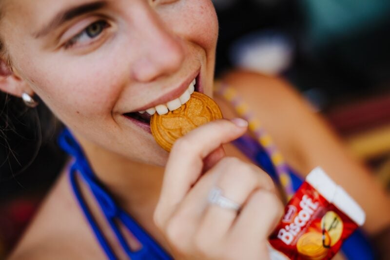 Festivalbesucherin beißt in einen Biscoff-Keks in Medaillen-Form bei Tomorrowland