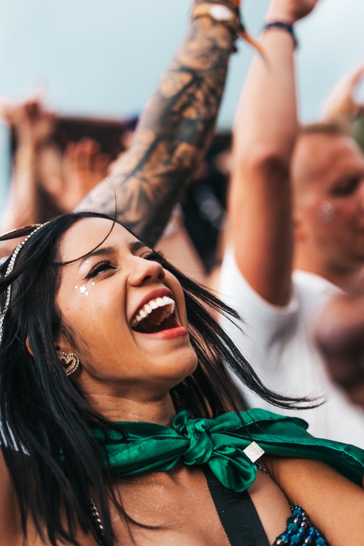 Lachende Festivalbesucherin mit grünem Halstuch in der Menge bei Tomorrowland