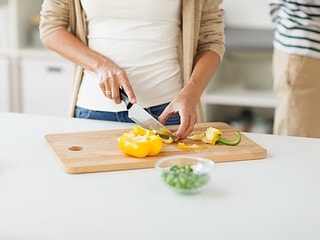 Frau schneidet Gemuese in der Kueche