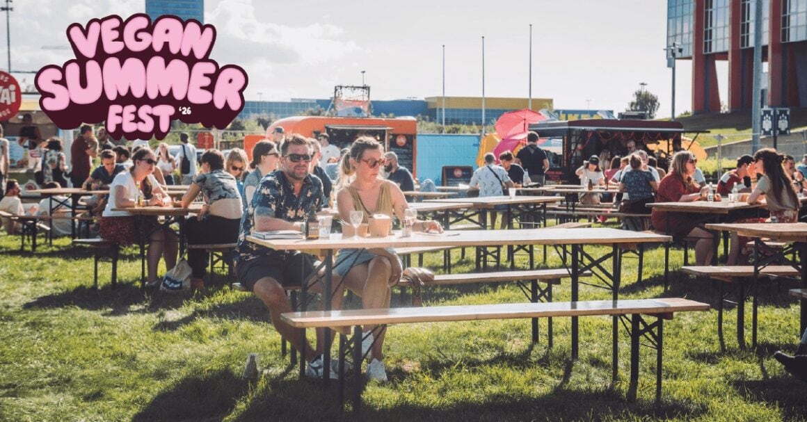 Besucherinnen und Besucher an Biertischen zwischen Foodtrucks beim Vegan Summer Fest in Gent