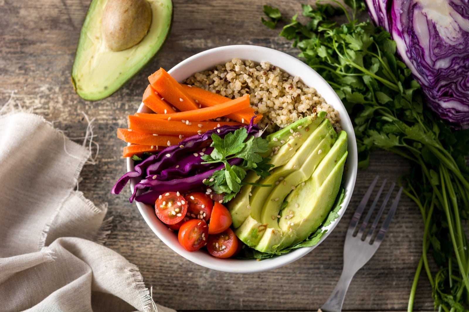 Vegane Bowl mit Quinoa und frischem Gemüse auf Holztisch