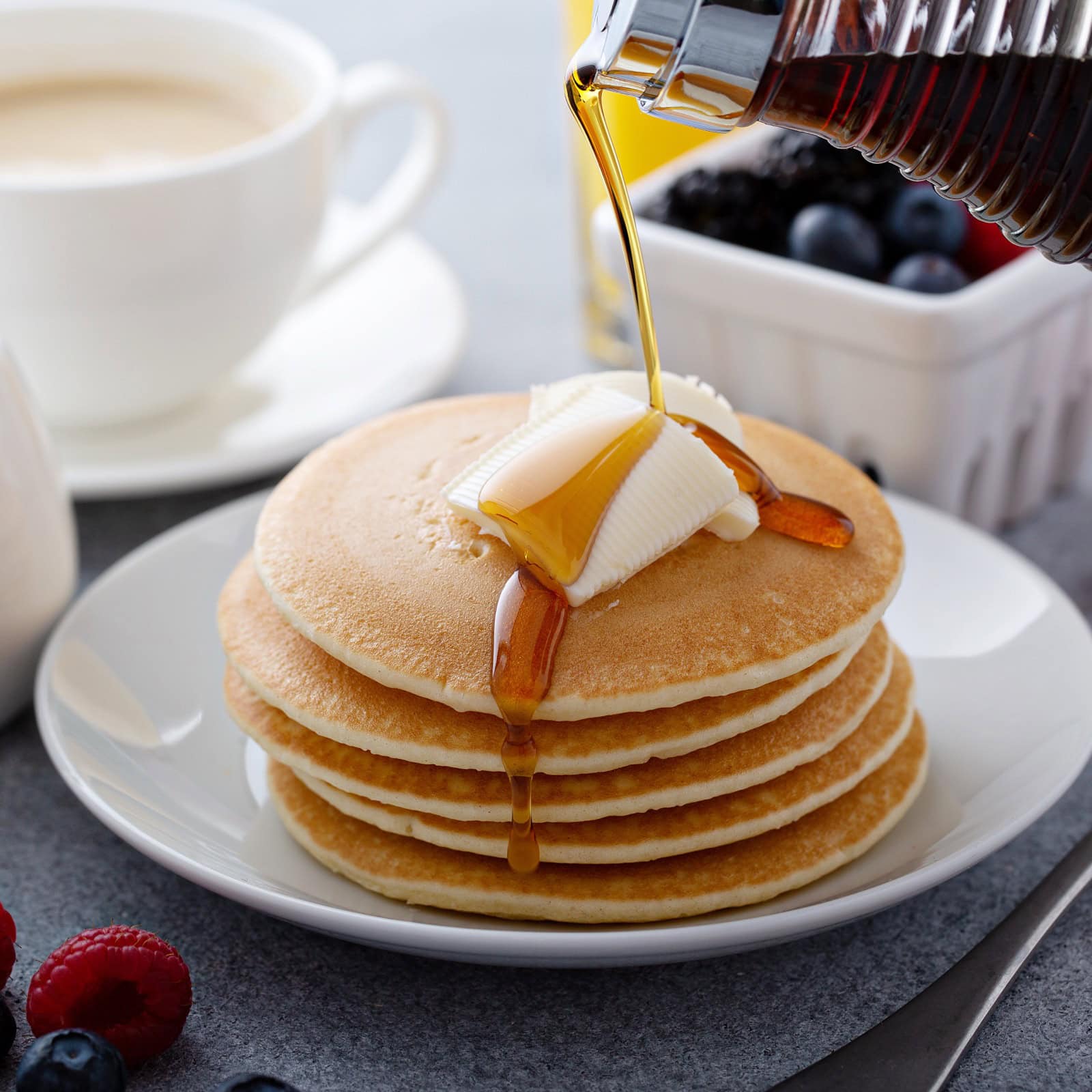 Sirup wird über einen Stapel Pancakes gegossen