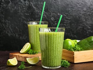 Gruene vegane Smoothies mit Obst und Gemuese in Glaesern