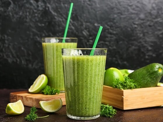 Gruene vegane Smoothies mit Obst und Gemuese in Glaesern