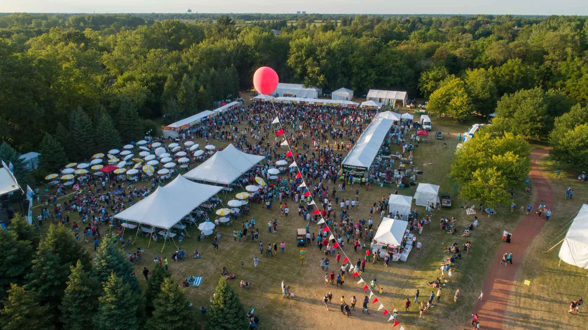 Aerial view of the Veggie Fest Chicago festival grounds with white tents and crowds in Danada South Park, Lisle