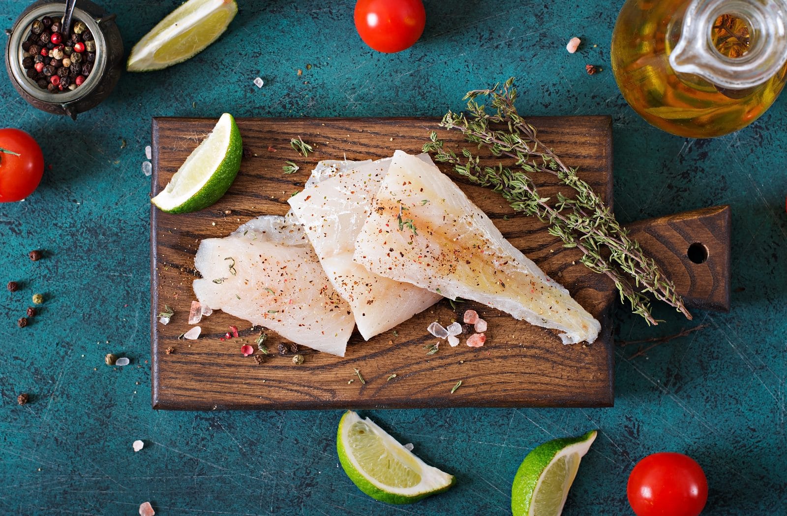 A raw white fish fillet on a wooden board