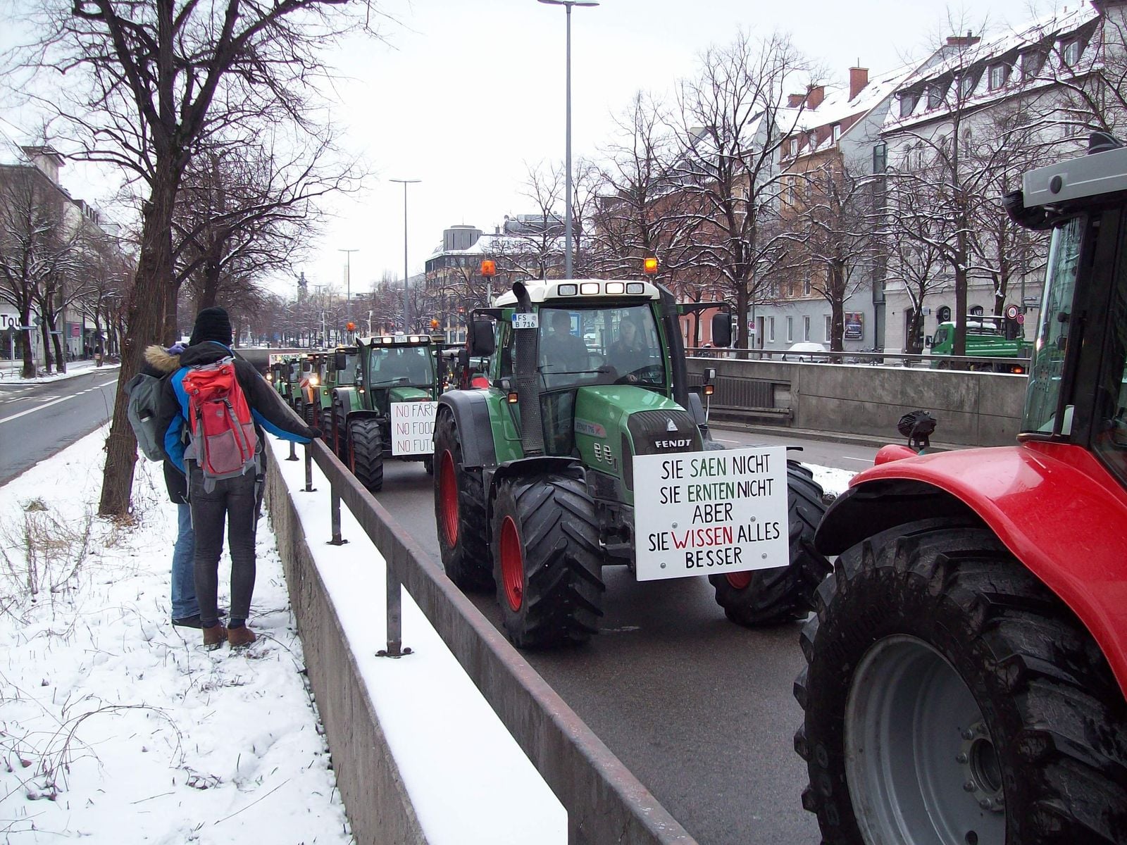 A column of tractors with protest signs in a snowy city centre