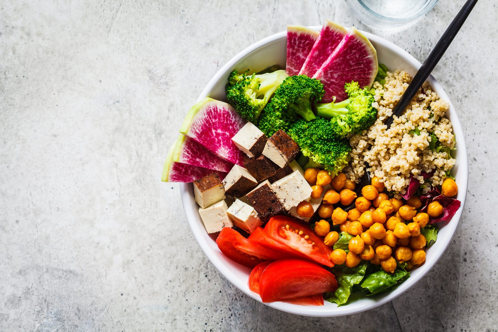 Bowl mit Quinoa, gerösteten Kichererbsen, Tofu und Gemüse von oben