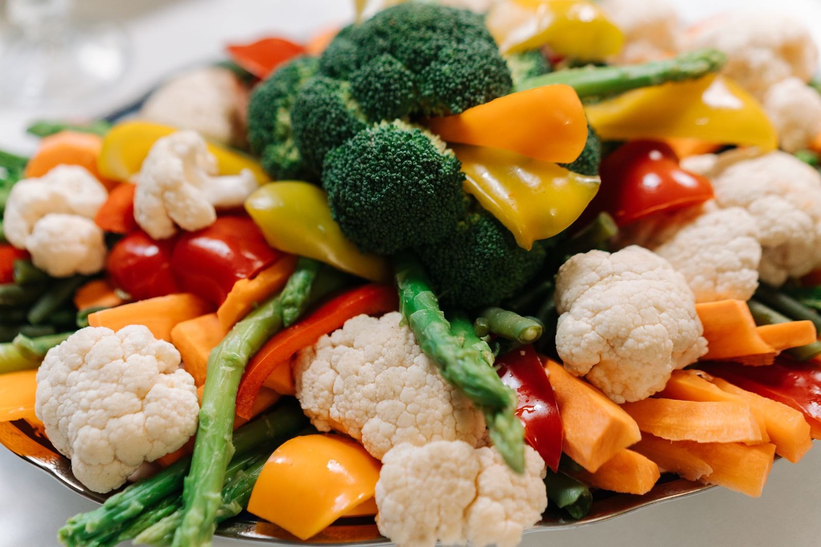 Plate of steamed broccoli, cauliflower, carrots and peppers