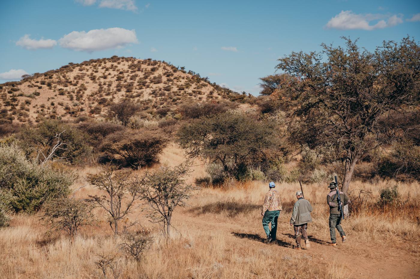Großwildjäger mit Gewehr auf der Pirsch in der afrikanischen Savanne