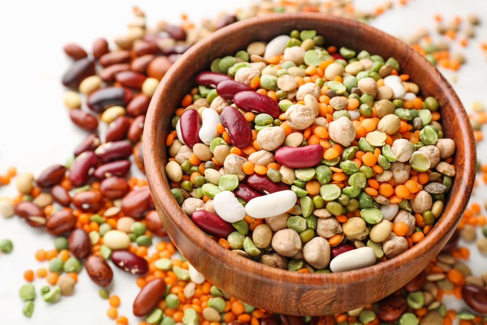 Wooden bowl of mixed pulses: chickpeas, red and white beans, green and red lentils