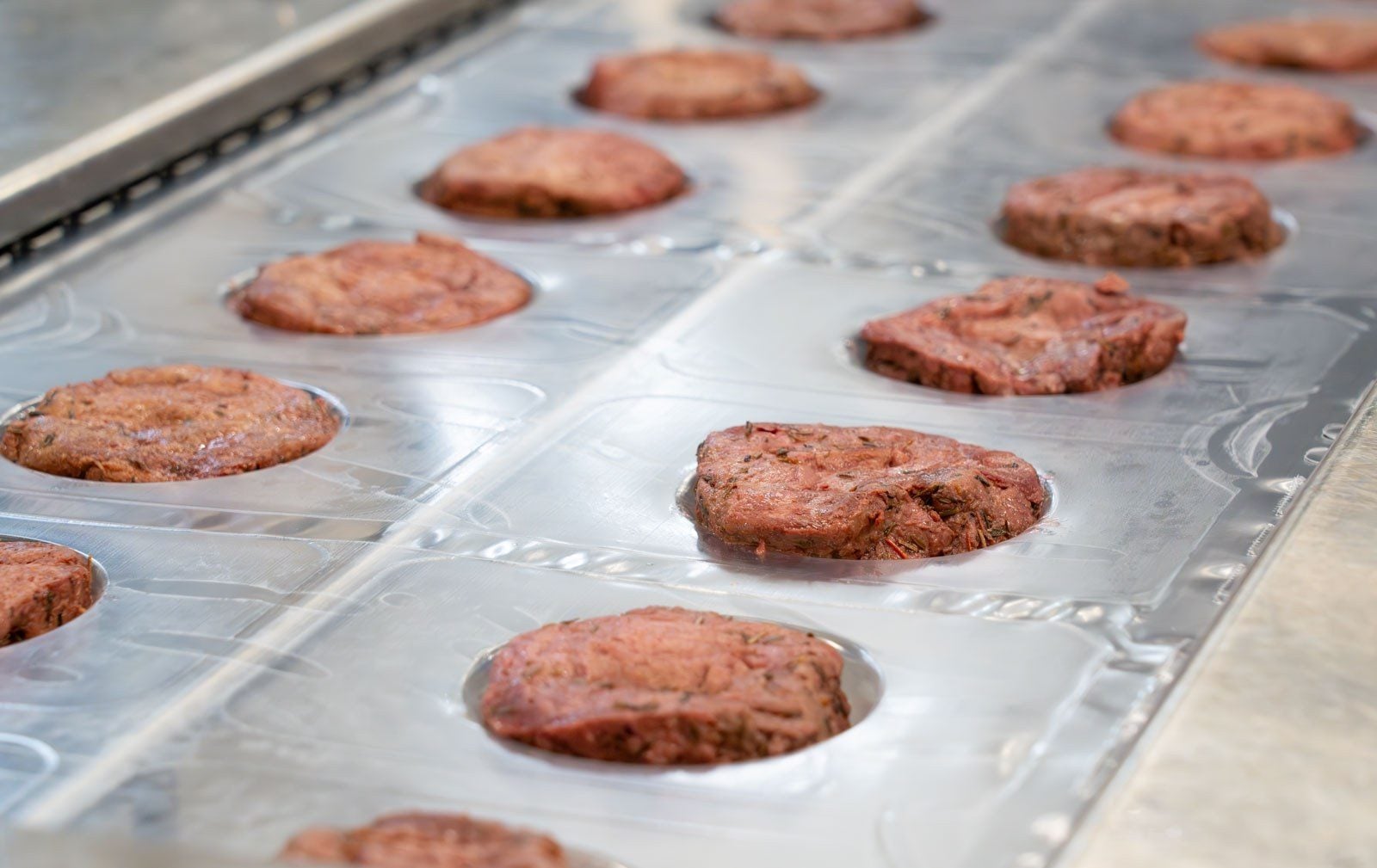 Pflanzliche Steaks von Planted liegen in Reihen auf einem Produktionsband