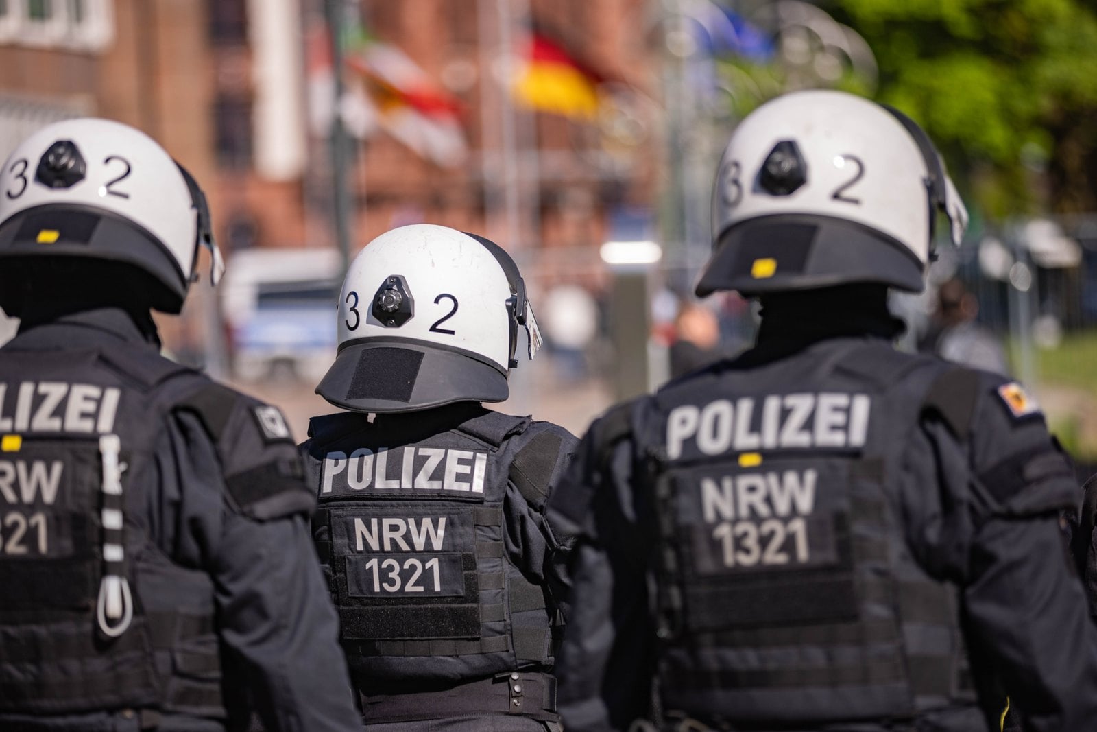 Drei Polizeibeamte in Schutzausrüstung von hinten bei einer Demonstration