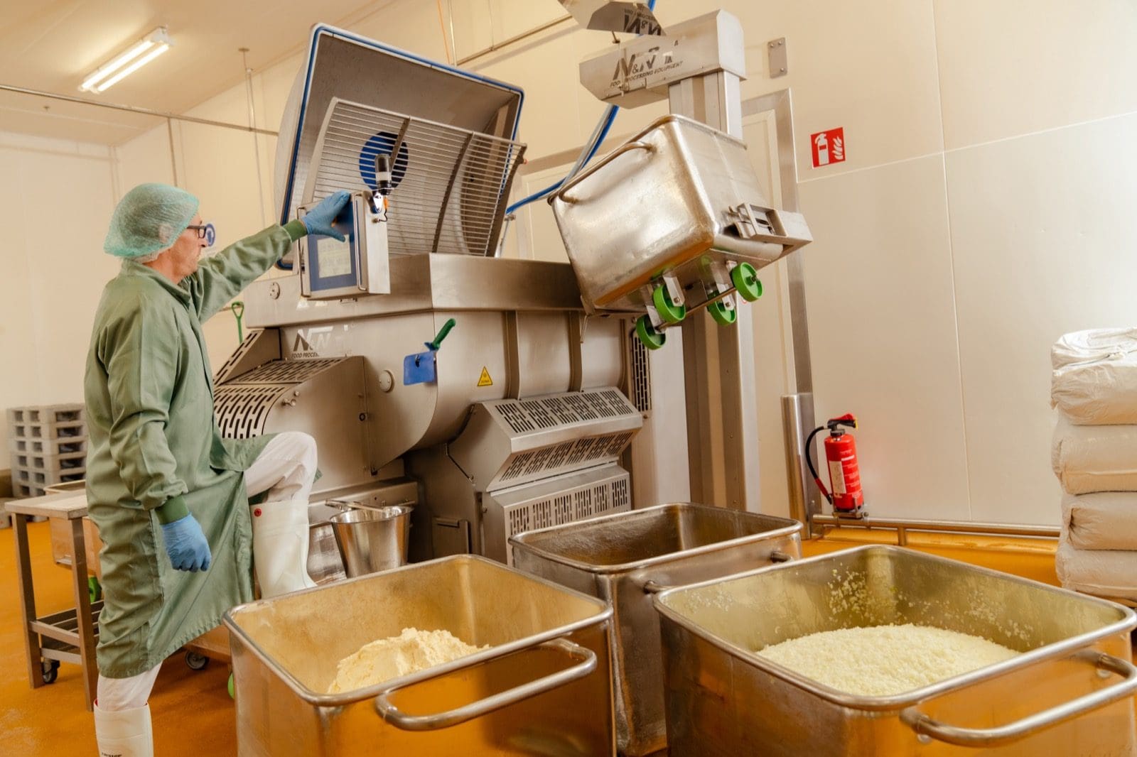 Mitarbeiter befüllt eine Maschine mit der Grundmasse für vegane Frikadellen