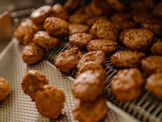 Fertige vegane Frikadellen laufen bei der Rügenwalder Mühle über das Förderband