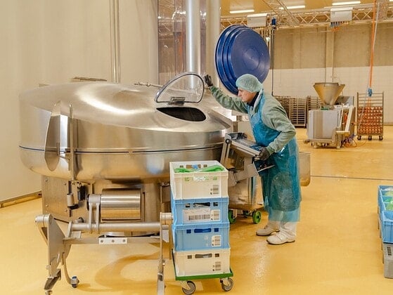 Mitarbeiterin an einem großen Kutter, in dem die Masse für den Veganen Schinken Spicker verarbeitet wird