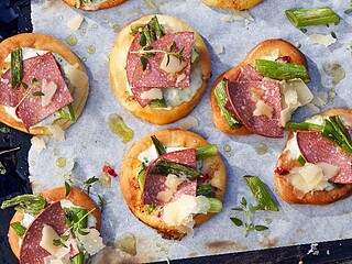 Cracker mit Scheiben veganer Salami, Frühlingszwiebeln und Kräutern auf einem Backblech
