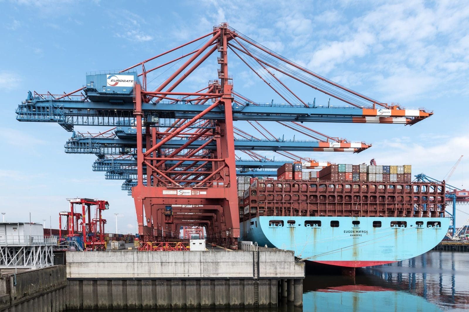 Containerschiff liegt unter Verladekränen an einem Hafenterminal