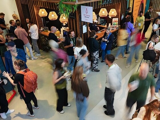 Viele Menschen mit grünen Lanyards im Café- und Netzwerkbereich des SFT Festivals, teils in Bewegungsunschärfe