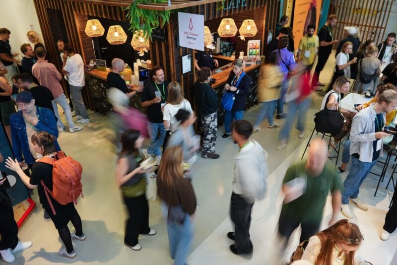 Viele Menschen mit grünen Lanyards im Café- und Netzwerkbereich des SFT Festivals, teils in Bewegungsunschärfe