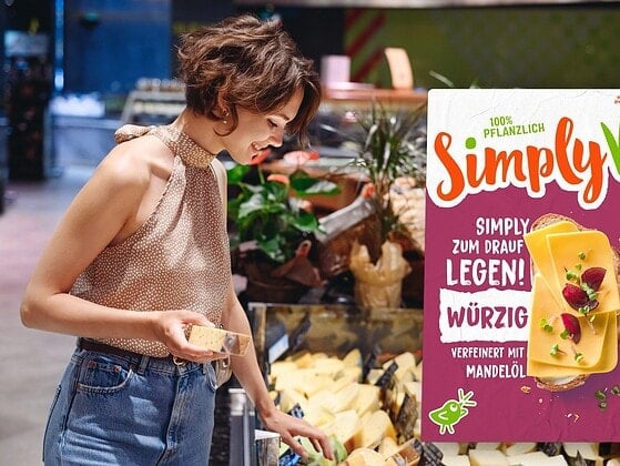 Frau an einer Käsetheke im Supermarkt, davor der Packshot der veganen Simply V Scheiben Würzig