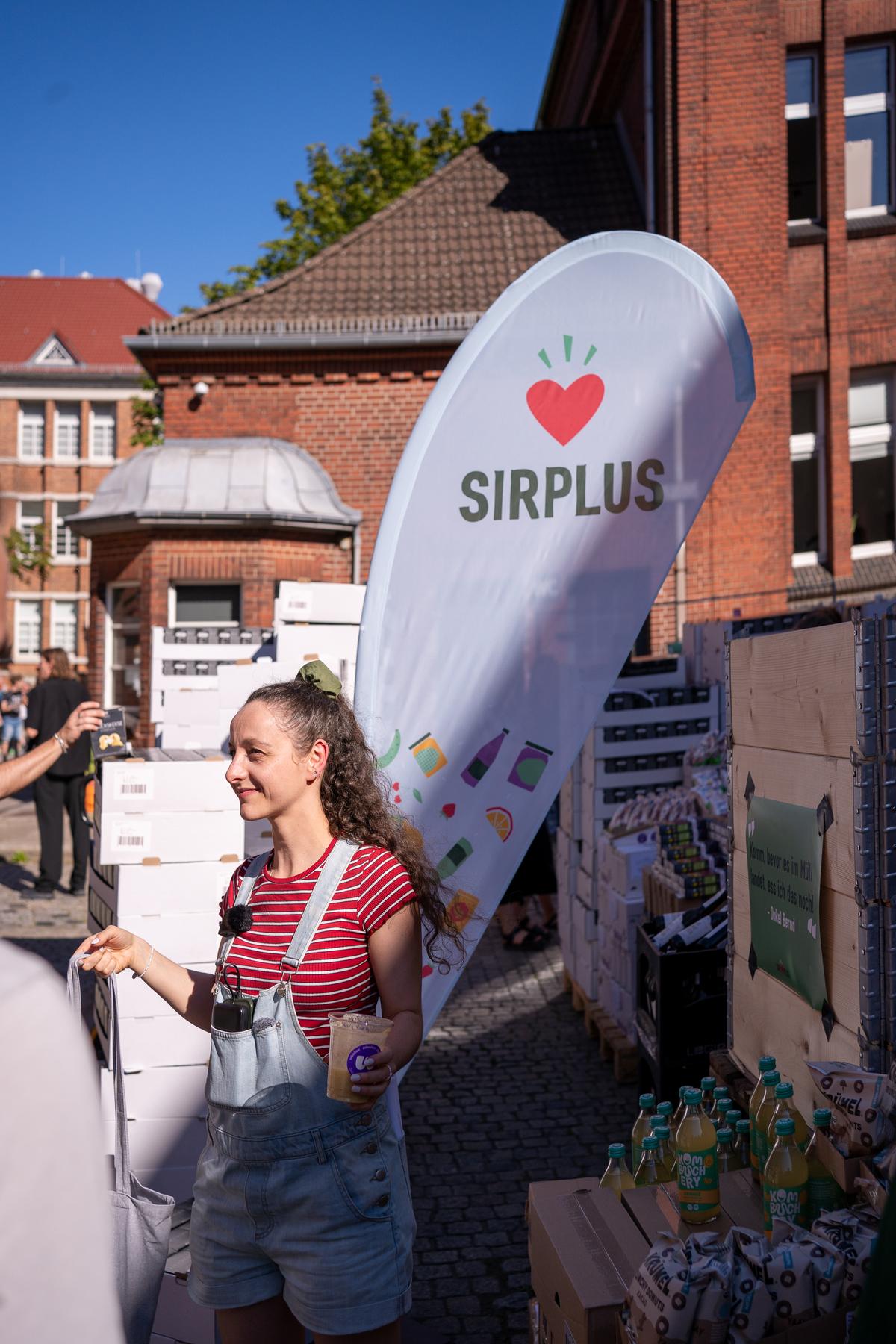 Besucherin am SIRPLUS-Stand mit Beachflag vor der Malzfabrik