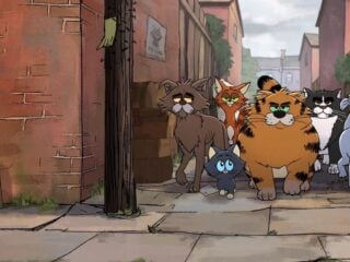 Sechs gezeichnete Katzen stehen in einer engen Gasse zwischen Backsteinhäusern, vorn ein kleines graues Kätzchen