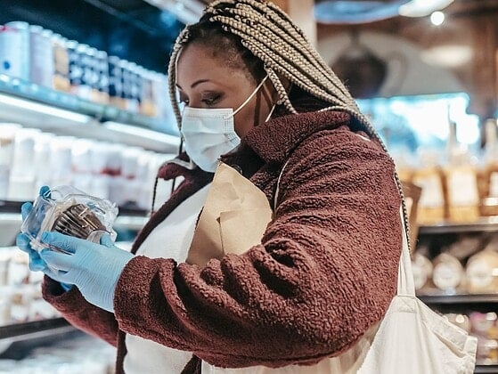 Frau steht im Supermarkt und liest die Rückseite einer Lebensmittelverpackung